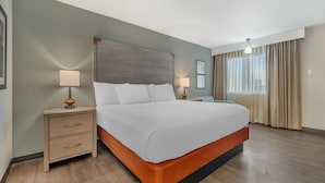 Een hotelkamer met een groot bed, houten nachtkastjes en een modern hoofdeinde.
