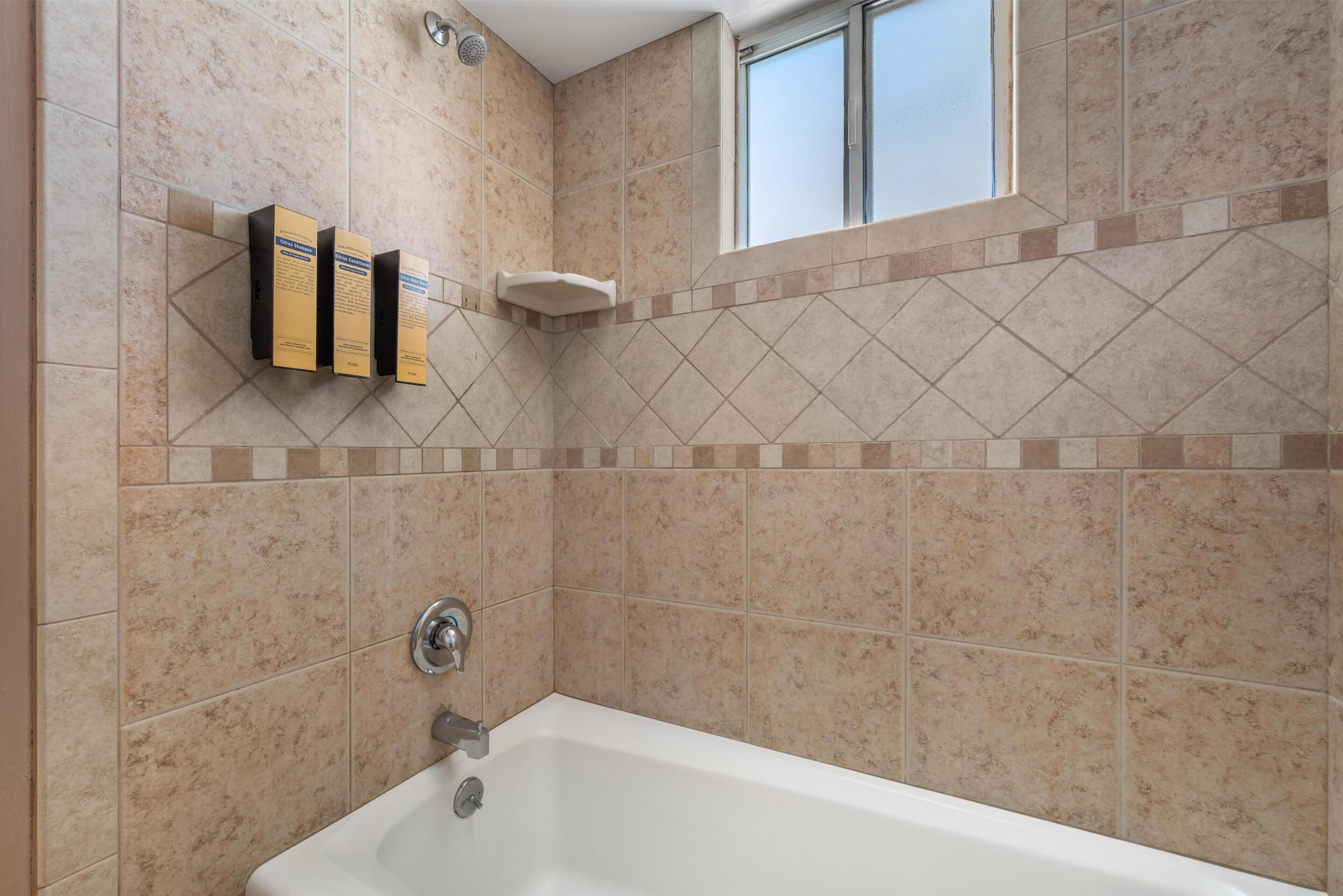 A bathroom with a bathtub, a showerhead, and a window.