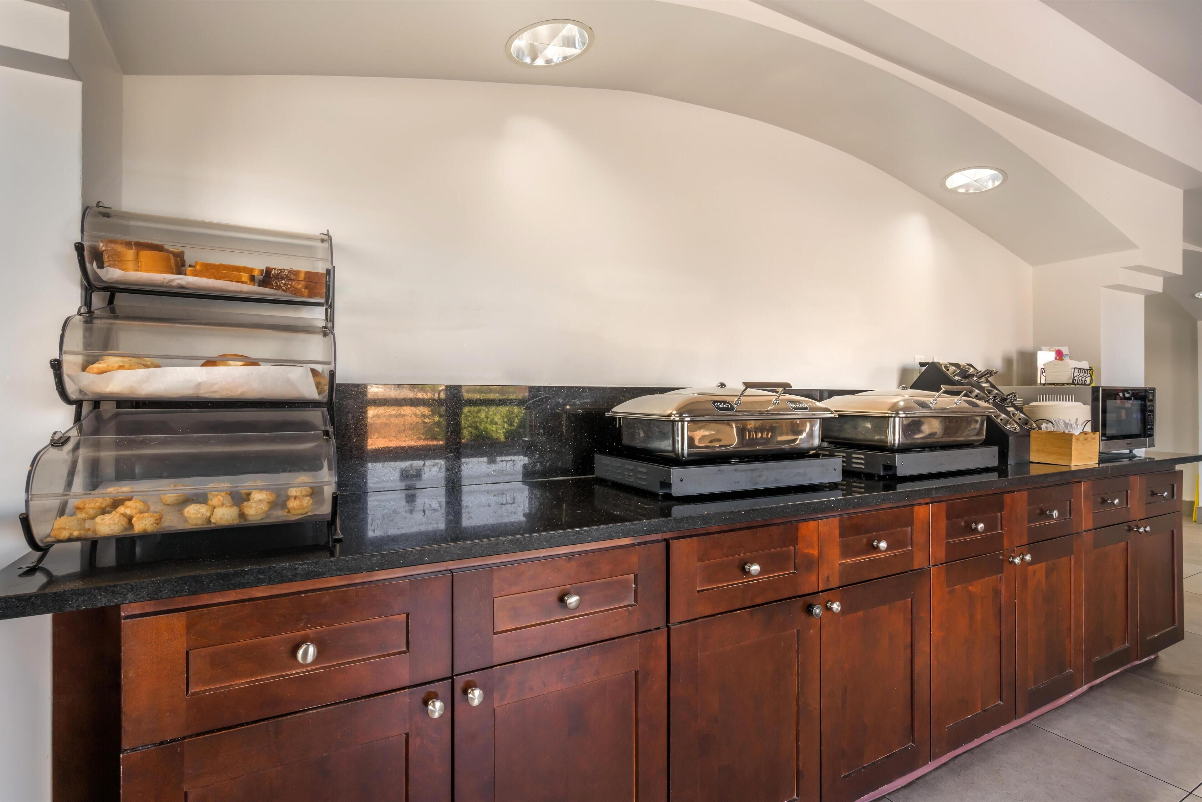 A kitchen with a marble countertop, wooden cabinets, and a built-in bread display.