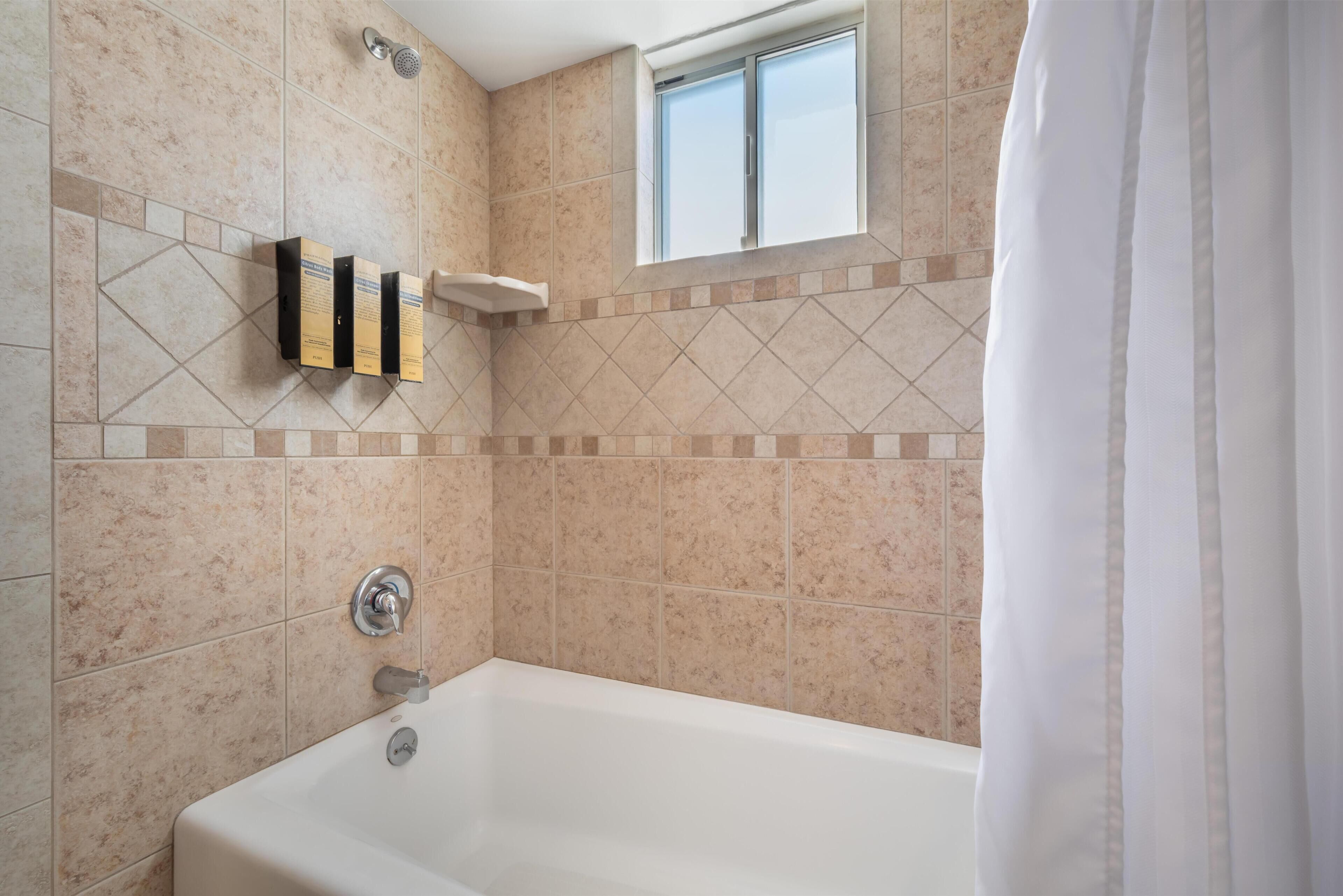 A bathroom with a bathtub, a window, and a showerhead.
