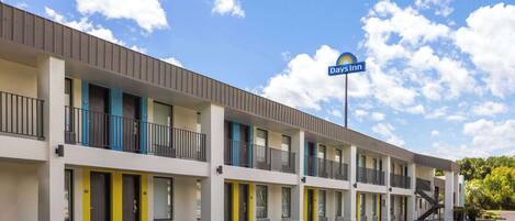 A motel with multiple rooms, a parking lot, and a clear sky.