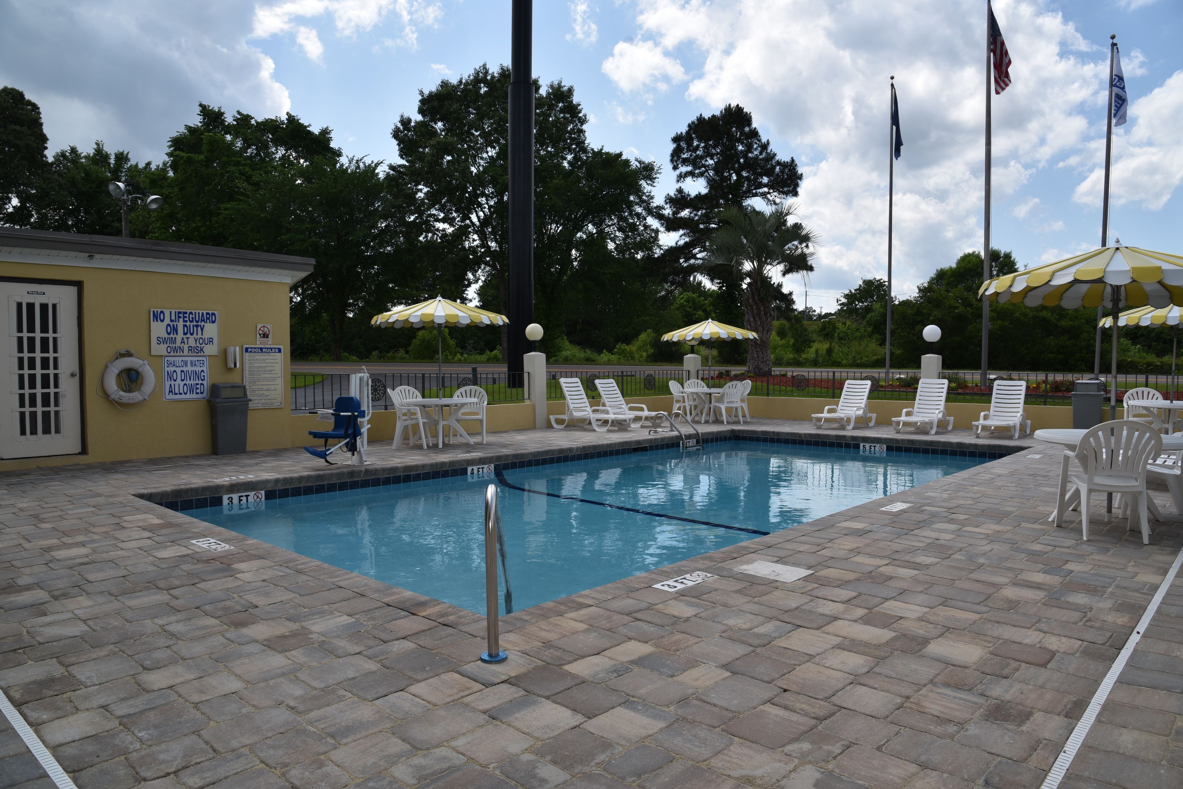 A swimming pool with lounge chairs, a lifeguard station, and flags.
