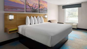 A hotel room with a large bed, a wooden headboard, wall-mounted lights, and a window with a view of the outdoors.