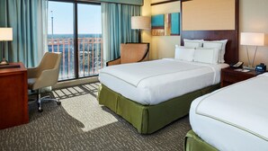 A hotel room with a large bed, a desk, a chair, and a view of the city.