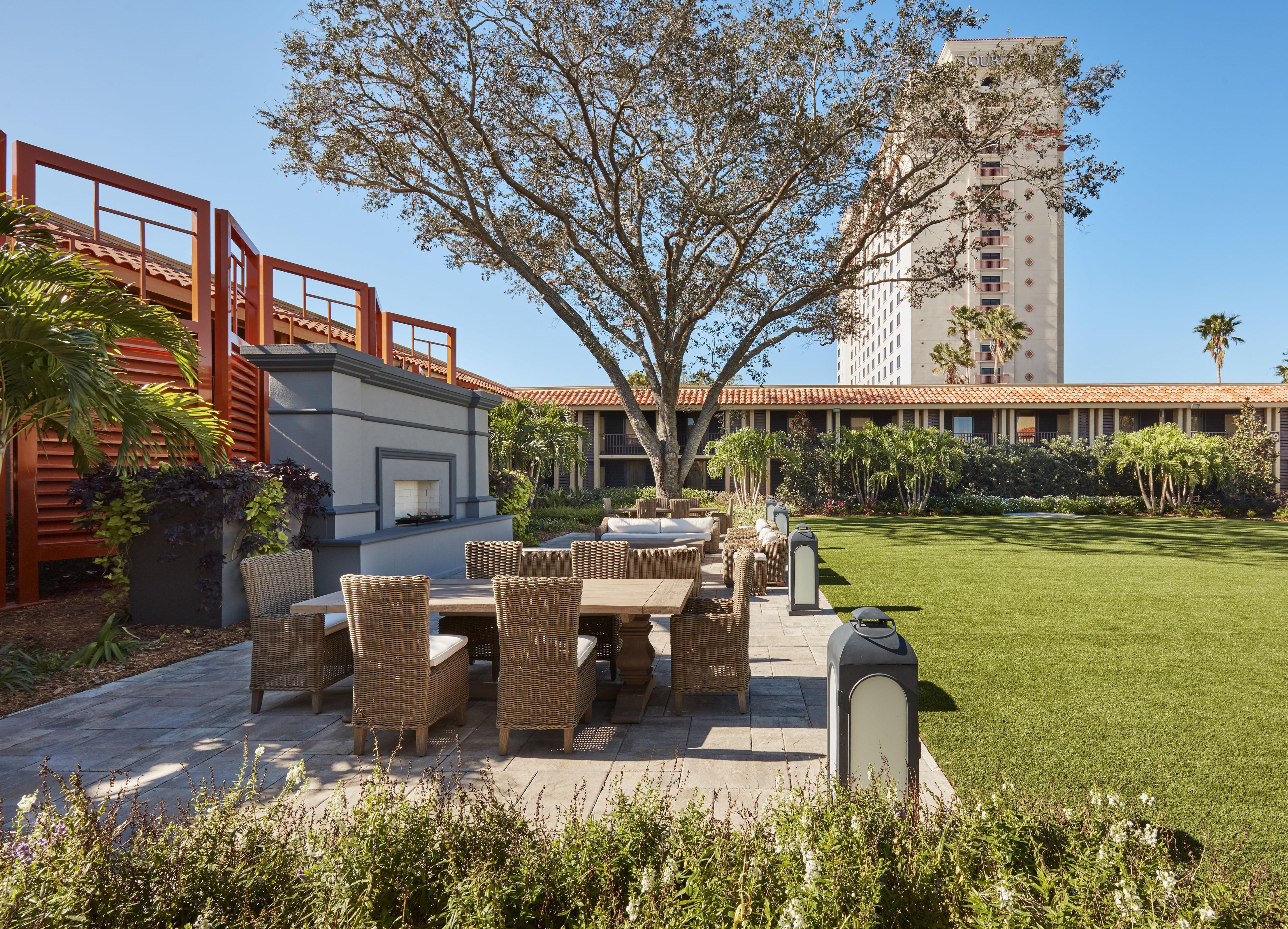 A courtyard with outdoor seating, a fire feature, and a tall building in the background.