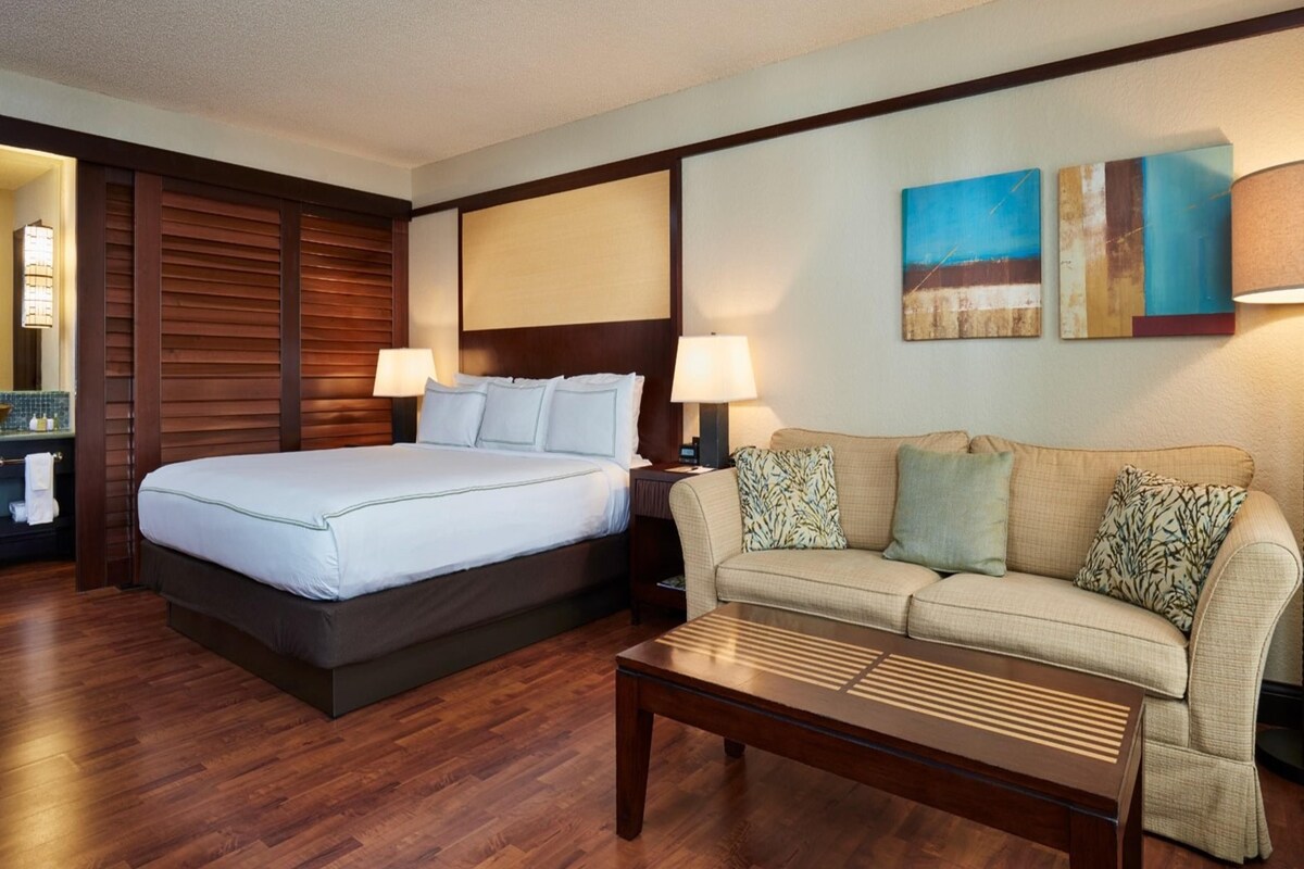 Ein Hotelzimmer mit Bett, einer Couch, einem Couchtisch und Bildern an den Wänden.