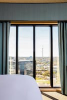 Een hotelkamer met een groot raam, een bed en gordijnen.