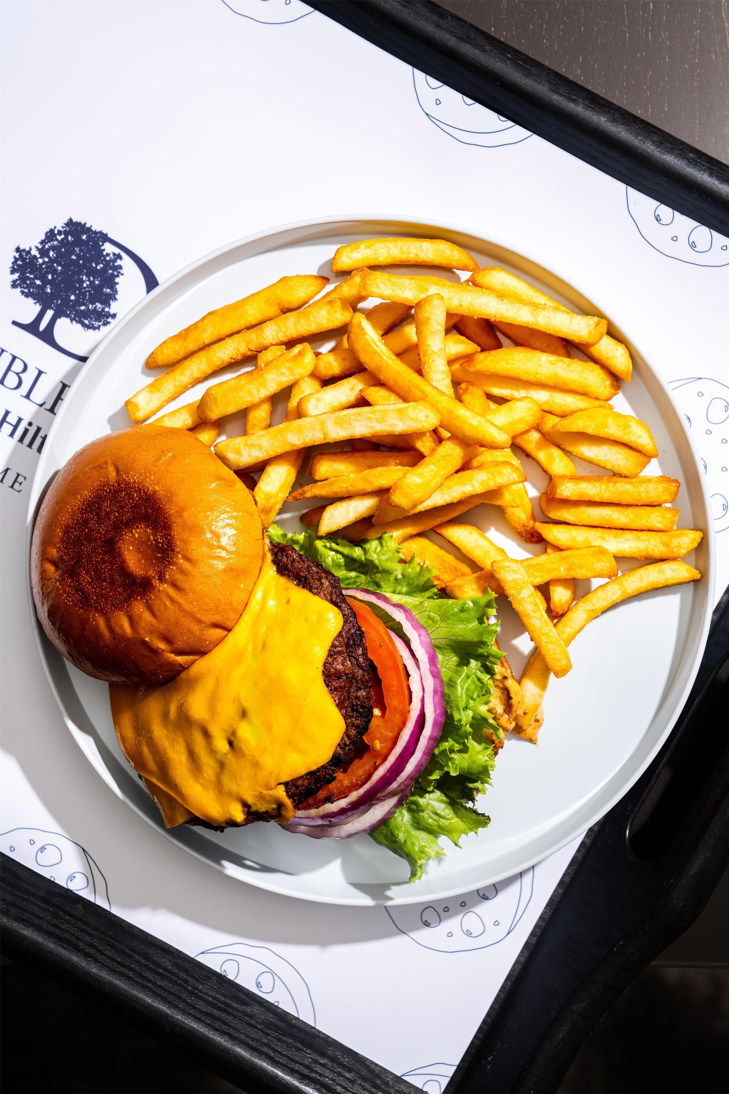 Un plato con una hamburguesa, papas fritas y una ensalada pequeña.