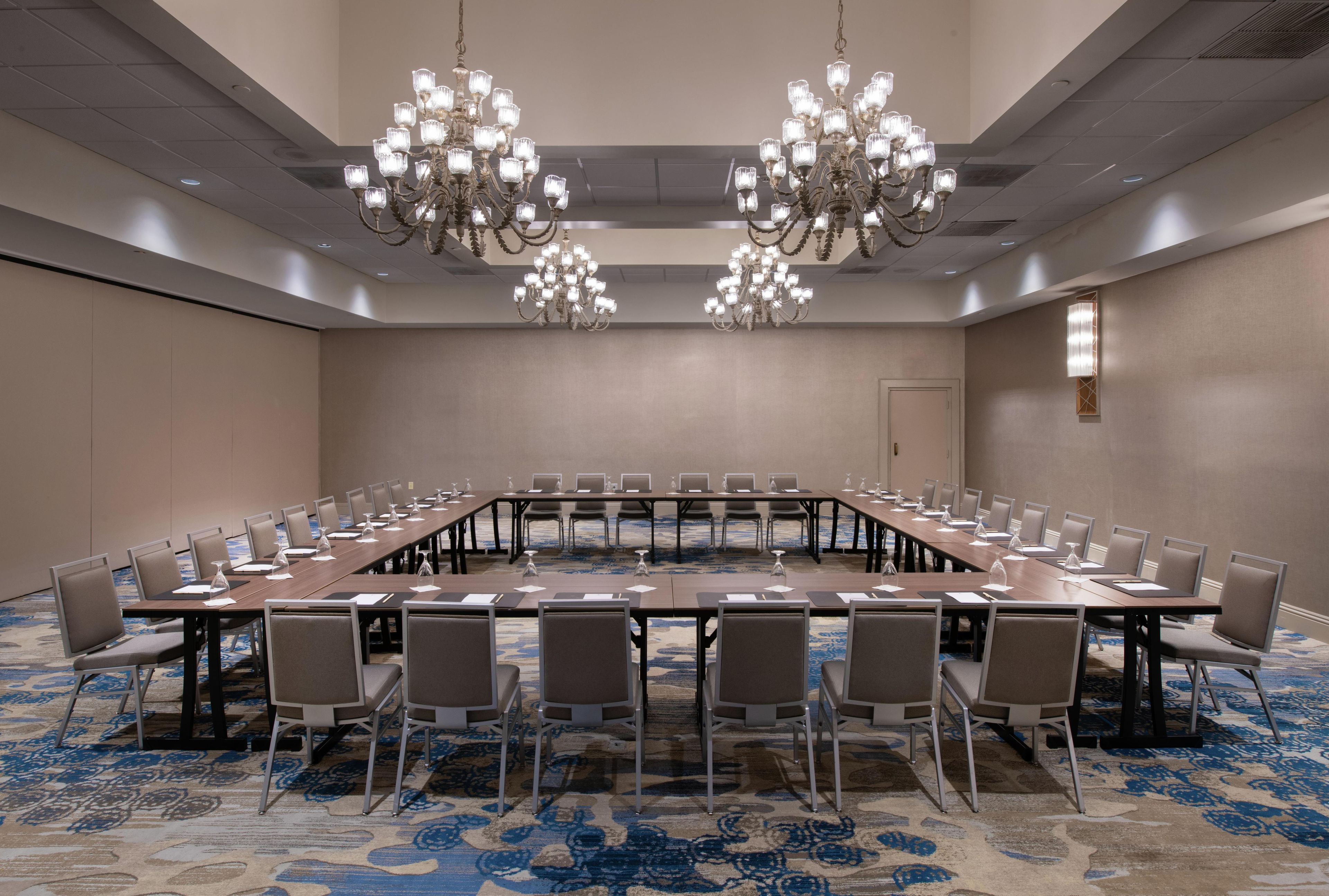 Un salón de conferencias con una larga mesa, varias sillas y candelabros.