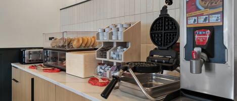 Een keukentrap met een wafelijzer, een koffieapparaat en een presentatie van wafels.