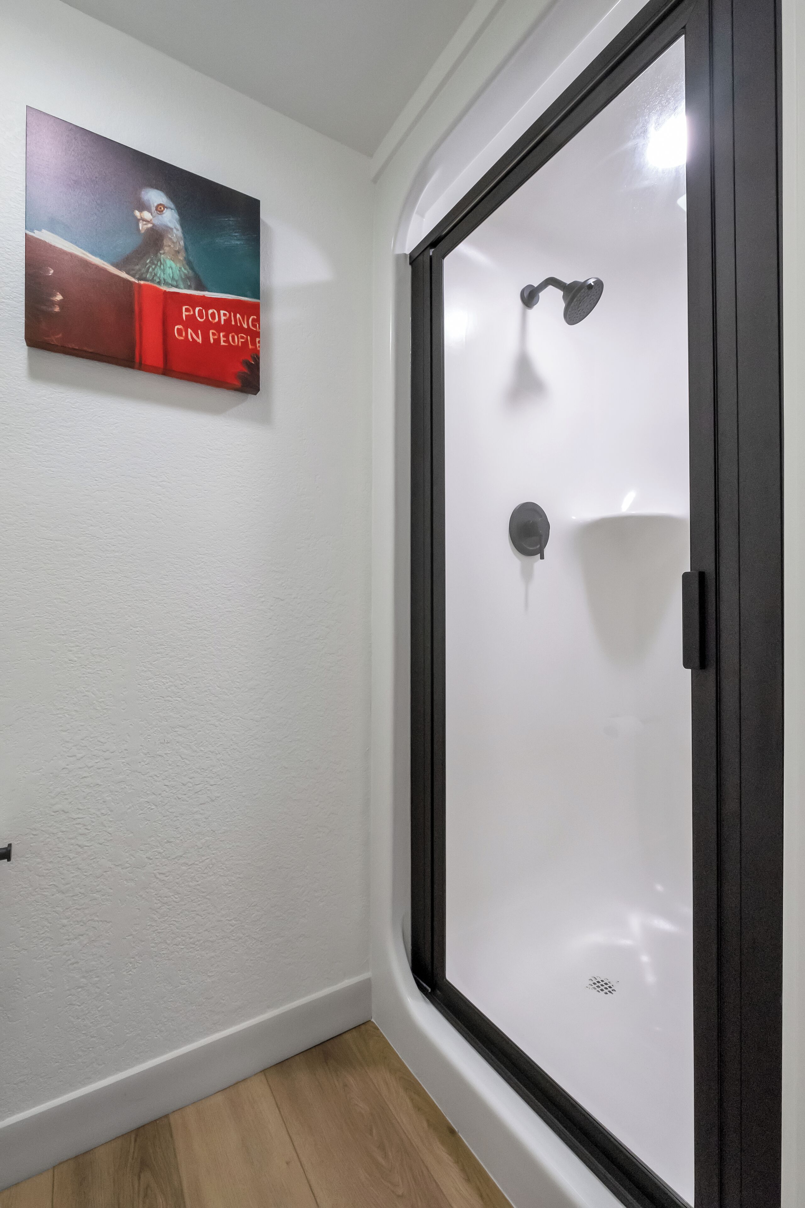 Ein Badezimmer mit einer weißen Dusche, einem Handtuchhalter und einer Wandleuchte.
