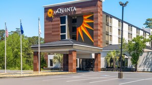 A La Quinta hotel with a distinctive sun design on the facade, a covered entrance, and a parking lot. - La Quinta Inn & Suites by Wyndham Myrtle Beach (Myrtle Beach)
