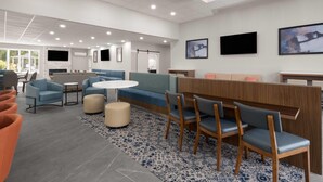 A modern lounge area with seating arrangements, a central table, and a patterned rug. - La Quinta Inn & Suites by Wyndham Myrtle Beach (Myrtle Beach)