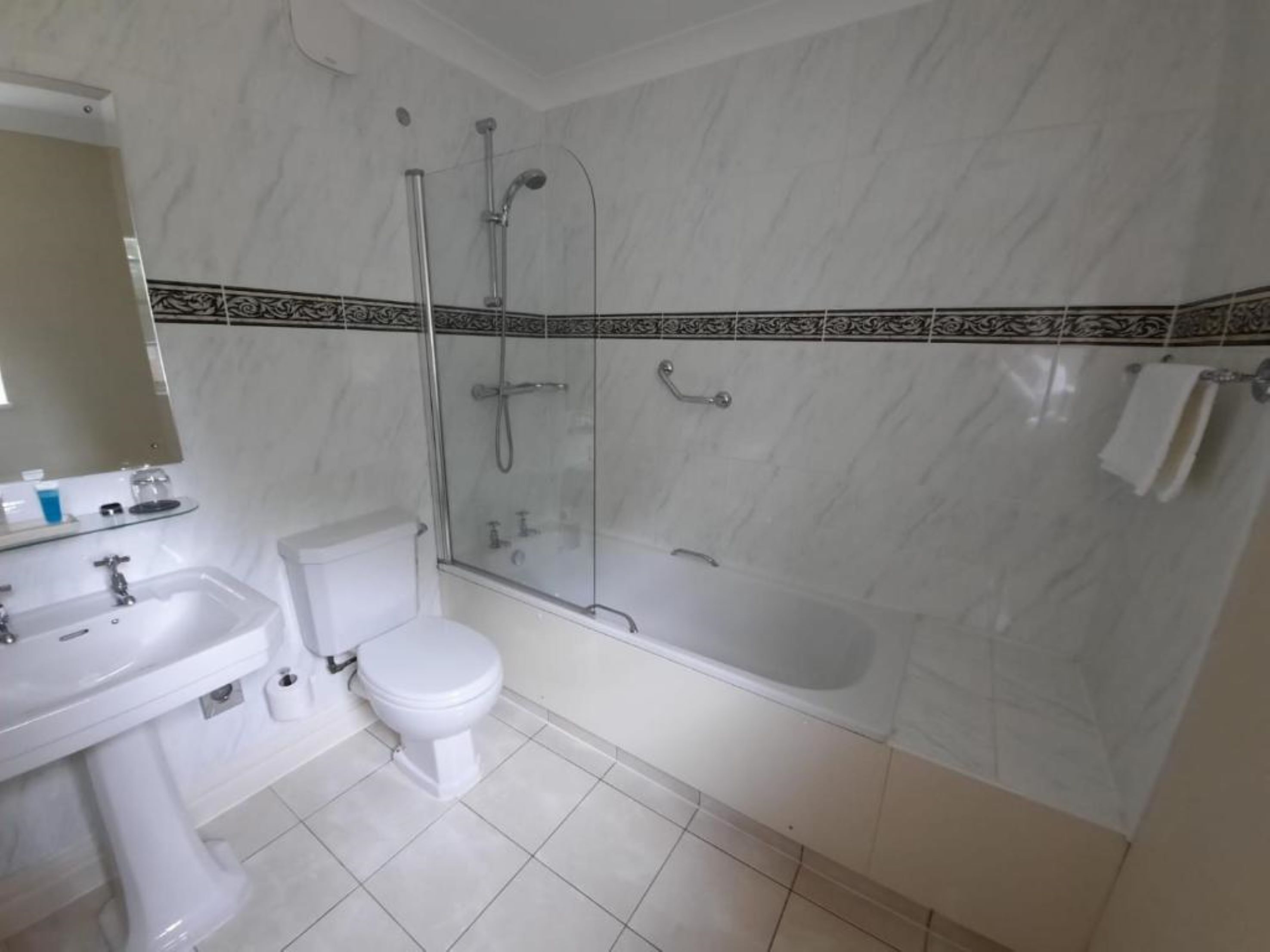 A bathroom with a toilet, sink, and shower area.