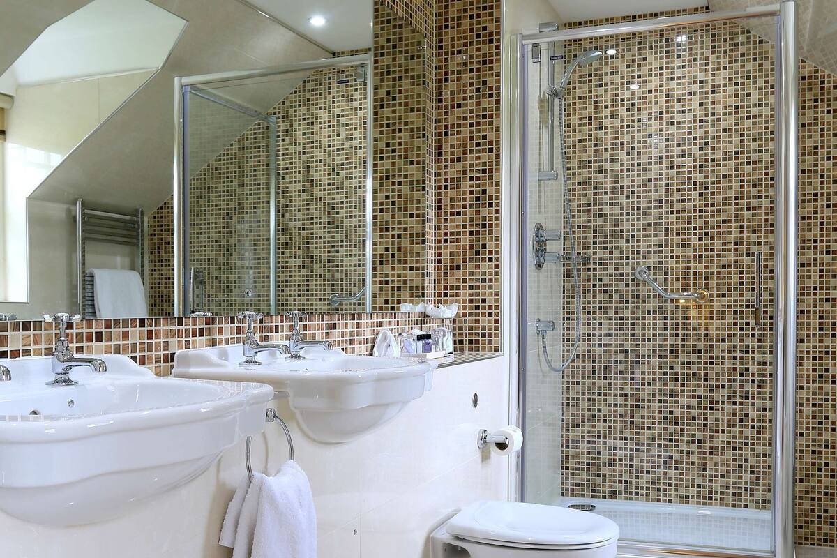 A bathroom with two sinks, a toilet, and a shower.