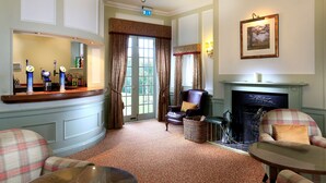 A room with a fireplace, a bar area, and two armchairs. - Macdonald Pittodrie House (Inverurie)