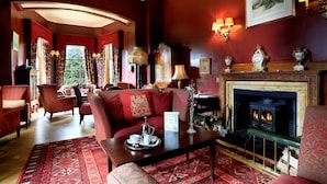 A traditional room with a fireplace, red sofas, a coffee table, and a patterned rug. - Macdonald Pittodrie House (Inverurie)