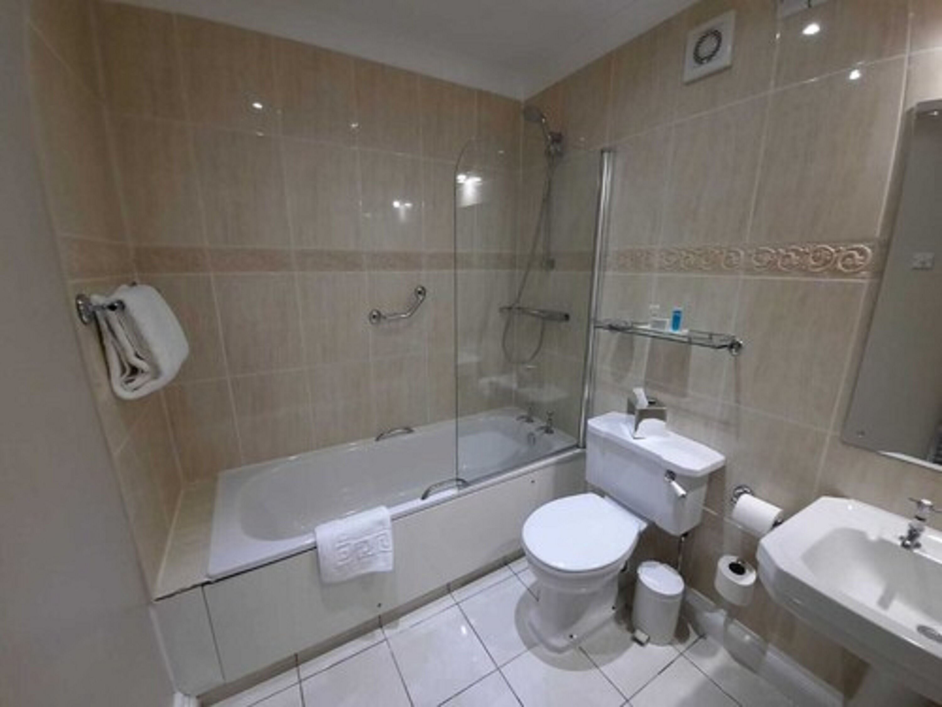 A modern bathroom with a glass-enclosed shower, a toilet, a sink, and a mirror.