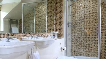 A modern bathroom with two sinks, a toilet, and a glass shower enclosure.