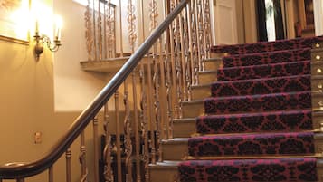 A grand staircase with ornate metal railings and patterned carpet.