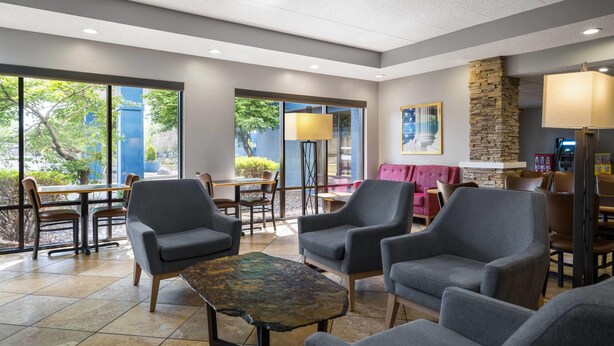 A modern indoor space with seating, a stone accent wall, and large windows.