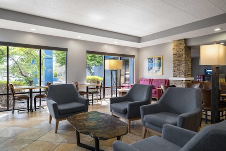 A modern indoor space with seating, a stone accent wall, and large windows.