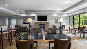 A restaurant with a fireplace, tables, chairs, and large windows.