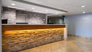 A reception area with a stone wall, a wooden counter, and a sign that reads 'AmericInn by Wyndham.'