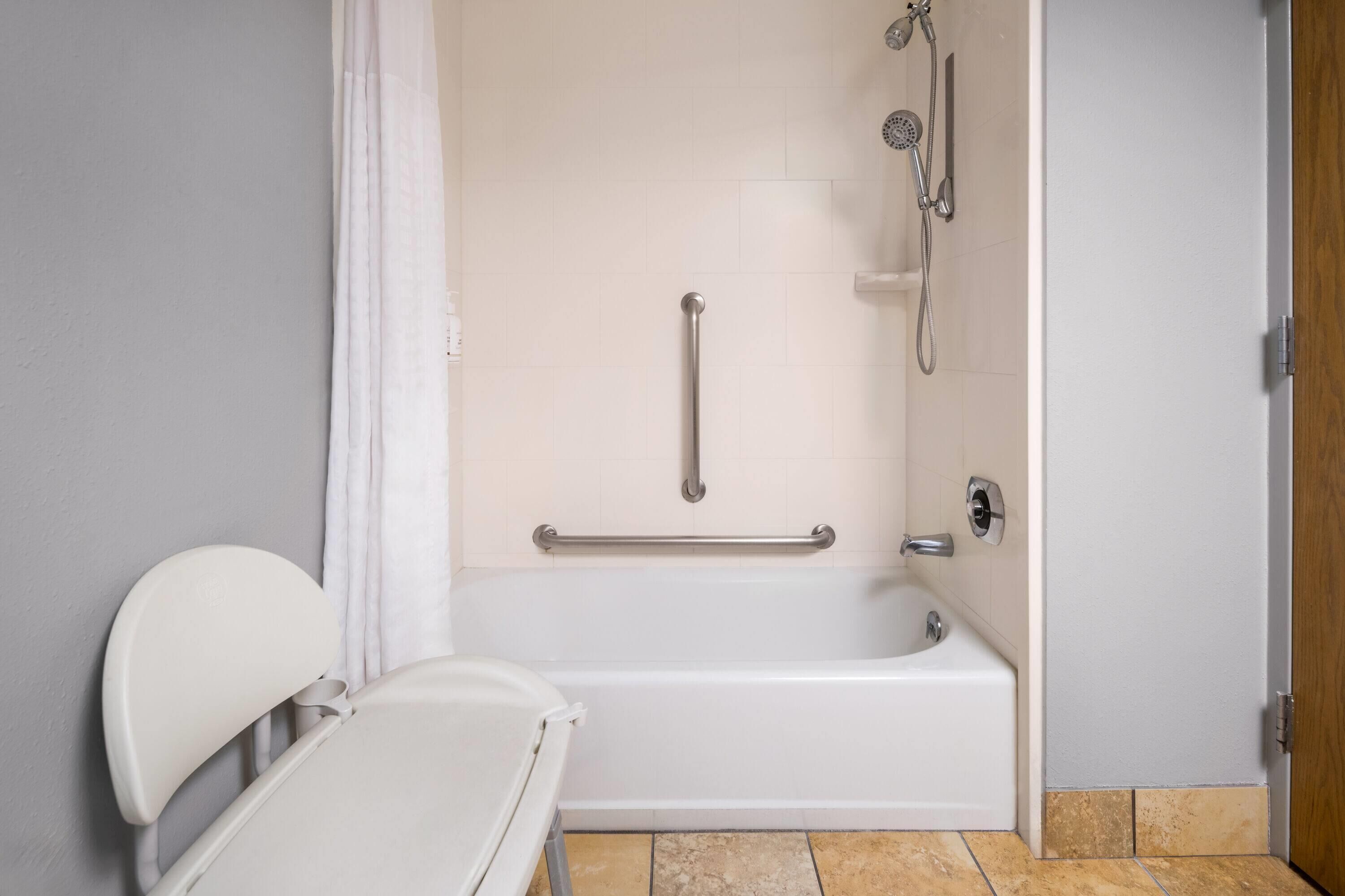 Un baño con bañera, ducha y barra de apoyo.