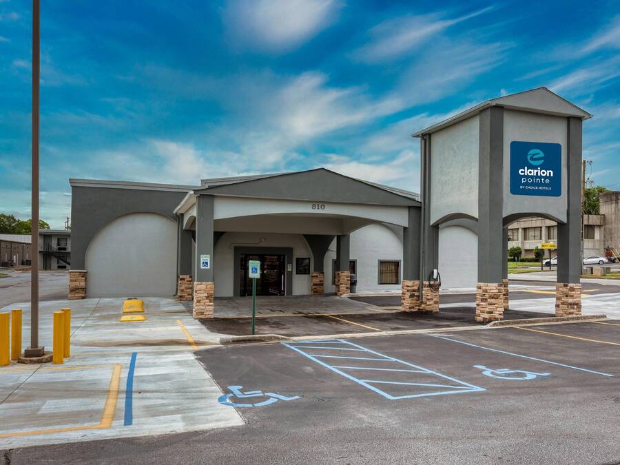 A hotel entrance with a parking lot, handicap parking, and a sign for Clarion Pointe by Choice Hotels.