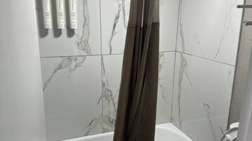 Un baño con bañera, inodoro y cortina de ducha.