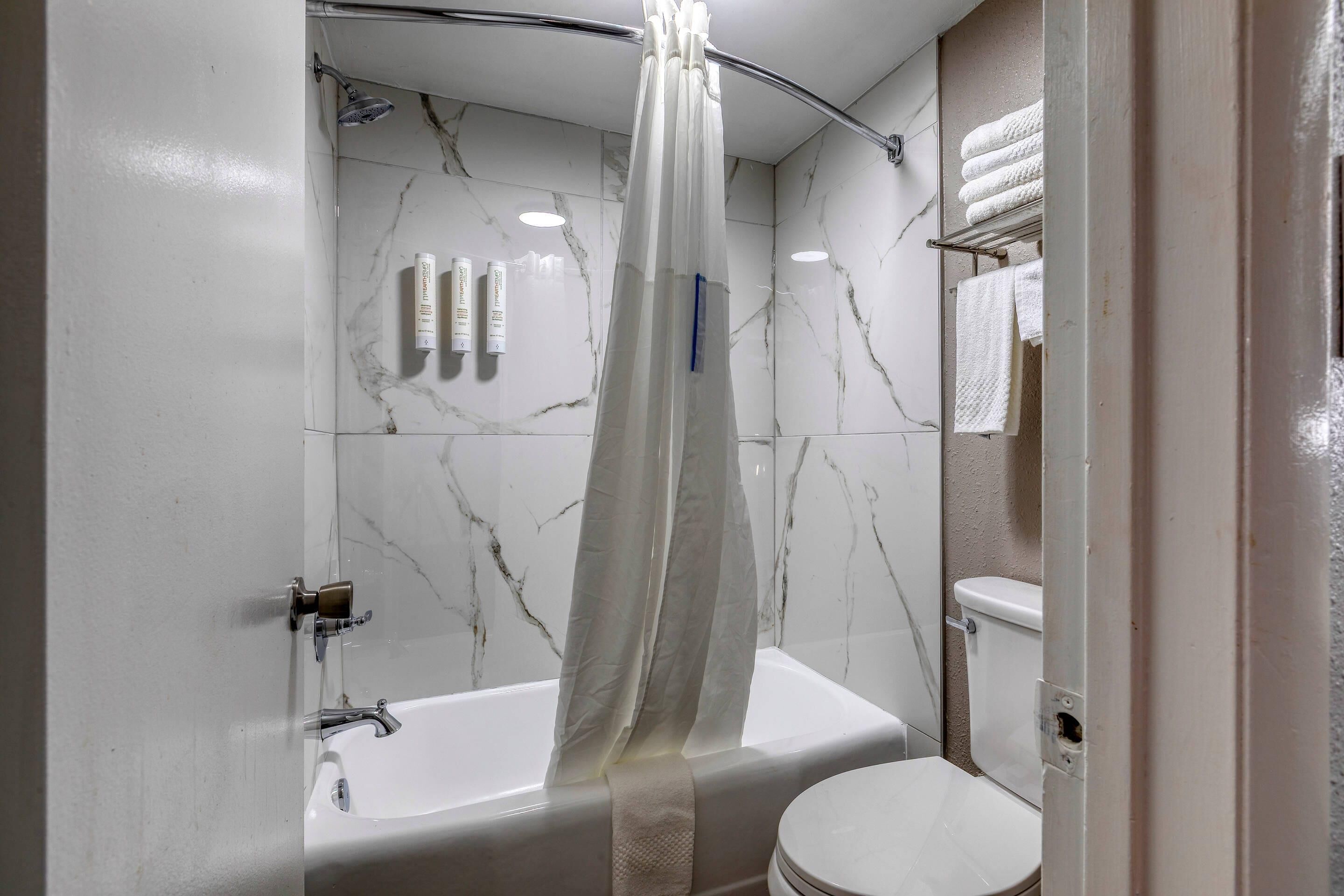 Un baño con bañera, inodoro y cortina de ducha.