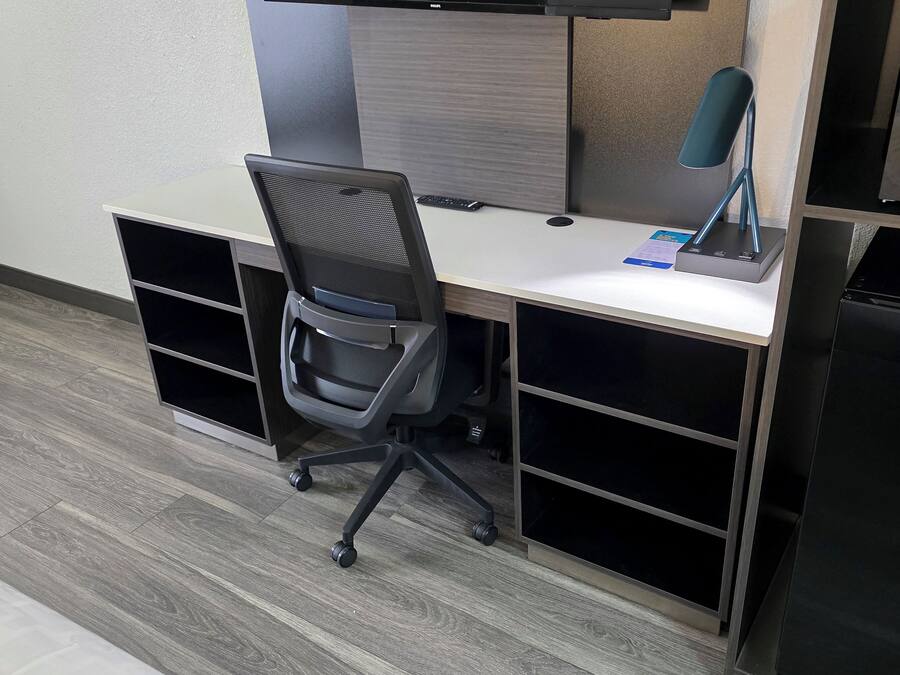 A modern office cubicle with a desk, chair, and a black refrigerator.