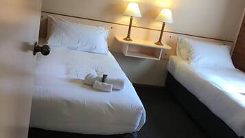Une chambre d’hôtel avec deux lits, une table de chevet avec des lampes et un tableau encadré au mur.