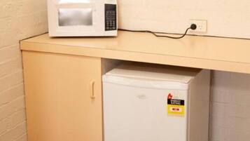 A small kitchenette with a microwave on a countertop and a mini-fridge below.