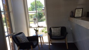 A small room with two chairs, a small table, and a window with a view of the outside. - Bega Downs Motor Inn (Bega)