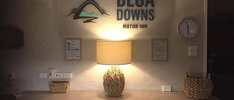 Una encimera de cocina con una lámpara, un reloj y un cartel que dice 'Bega Downs Motor Inn'.