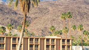 Un hotel con varios balcones, un campo de golf y palmeras.
