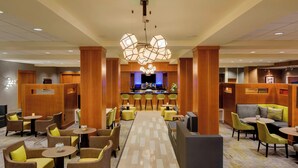 A hotel lobby with a central bar area, multiple seating arrangements, and a patterned floor. - Courtyard by Marriott Boston Logan Airport (Boston)