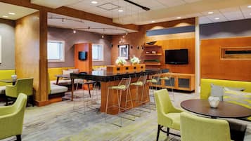 A modern hotel lobby with a bar area, seating, and a flat-screen TV.