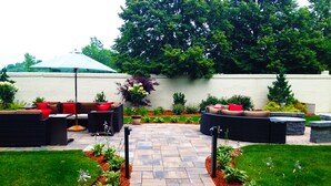 A patio area with a stone pathway, outdoor furniture, and a variety of plants. - Courtyard by Marriott Boston Logan Airport (Boston)