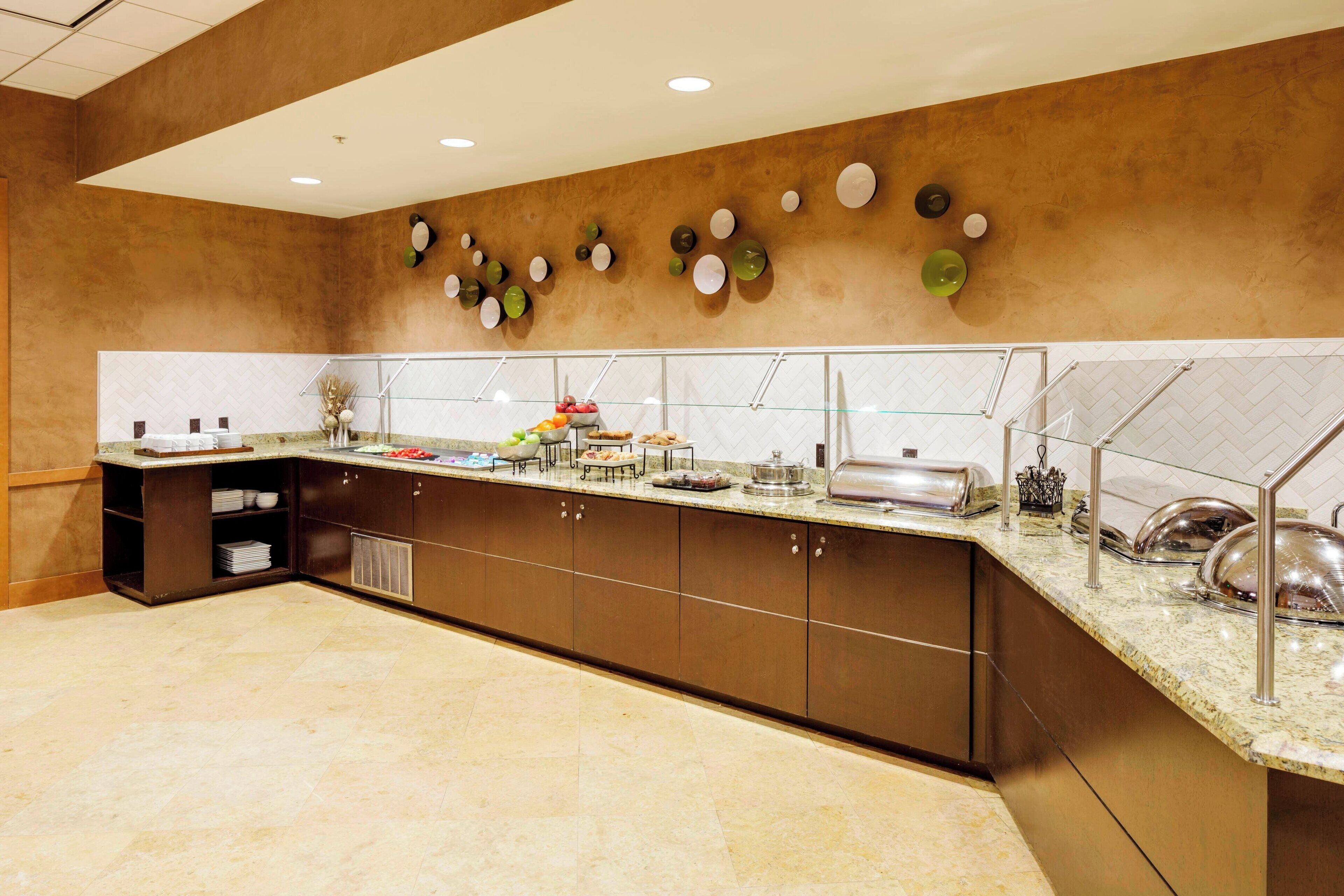 Una cocina moderna con encimera de mármol, electrodomésticos de acero inoxidable y una variedad de alimentos a la vista.
