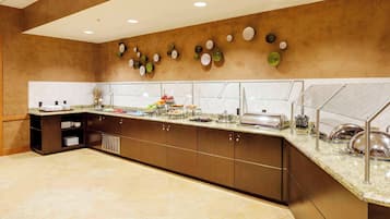 Una cocina moderna con encimera de mármol, electrodomésticos de acero inoxidable y una variedad de alimentos a la vista.