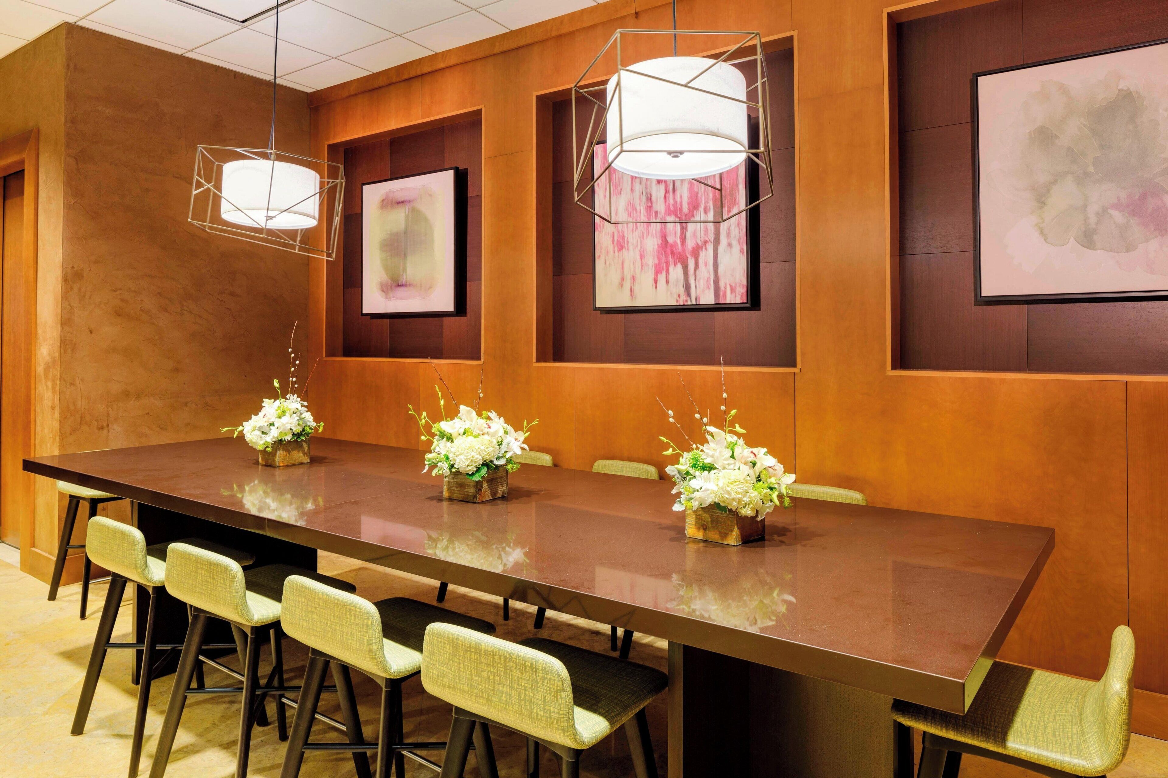 A conference room with a long table, chairs, and floral centerpieces.