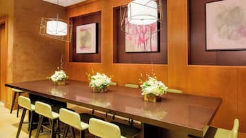 A conference room with a long table, chairs, and floral centerpieces.