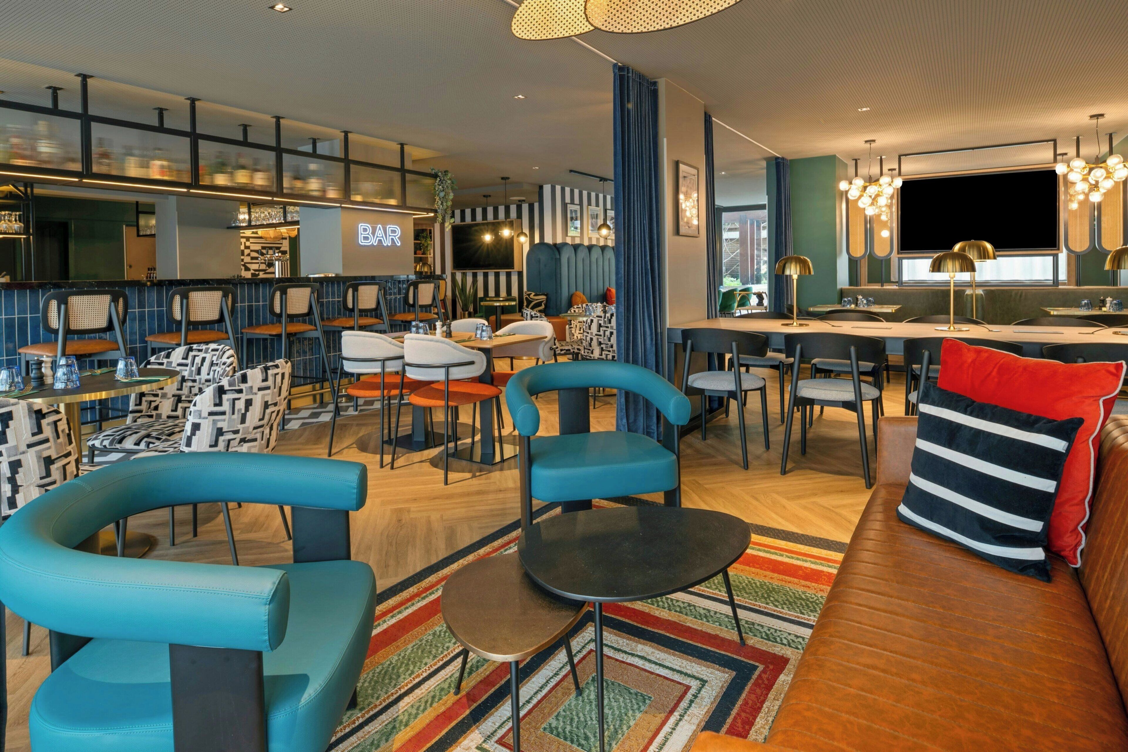 Un intérieur moderne comprenant un bar, des espaces de détente et un écran de télévision.