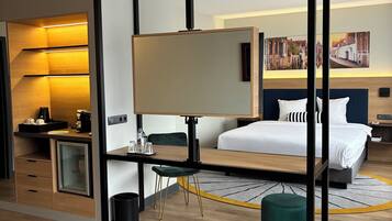 A modern hotel room with a bed, desk, chair, and a large mirror.