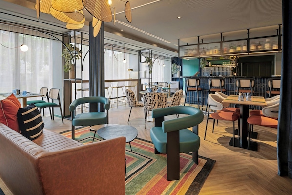 A modern interior with seating areas, a bar, and a kitchen visible in the background.