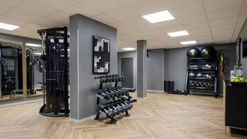 Ett gym med träningsredskap, en spegel och ett väggmonterat ställ med hantlar.