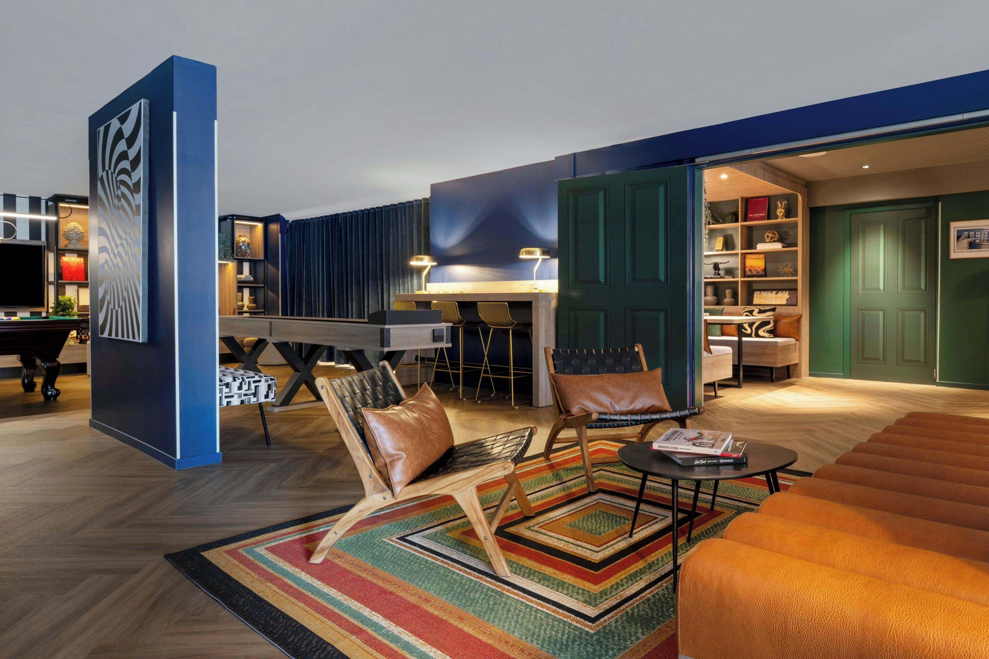 Una sala de estar moderna con mesa de billar, sillones de cuero y una estantería.